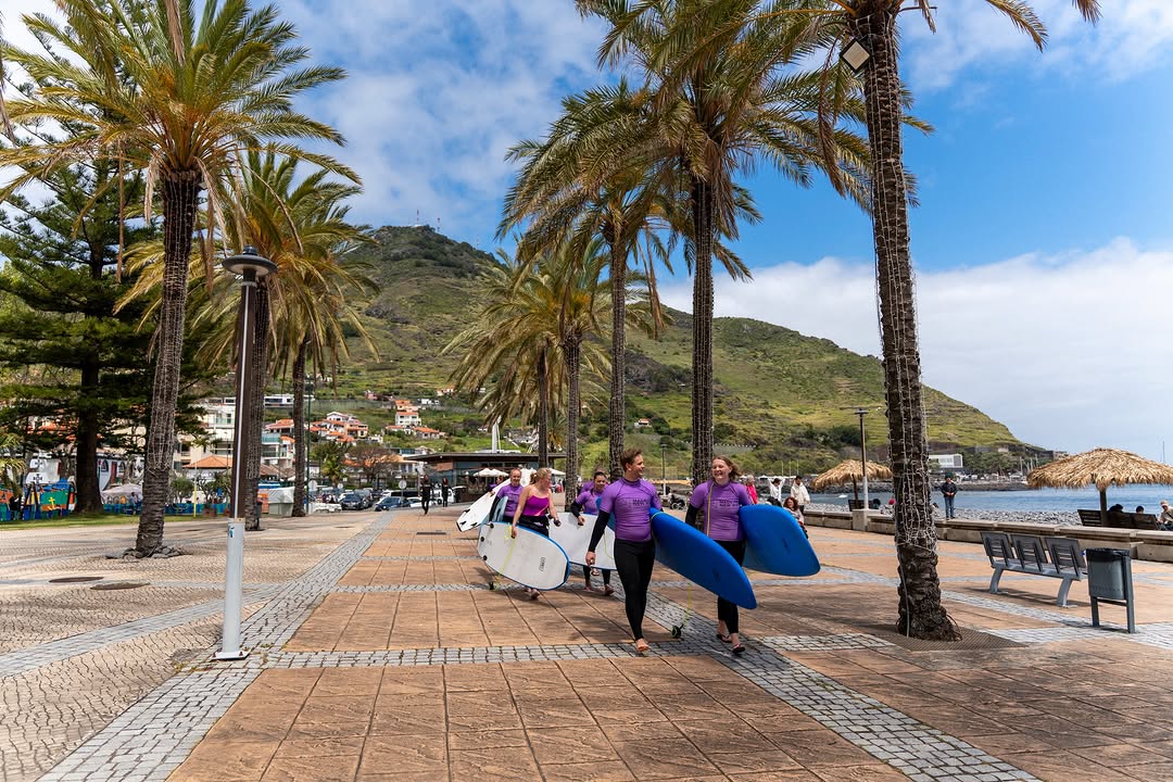 Group of happy surfers with their surfboards in front of Machico's beach about to start their group surf lessons in Madeira
